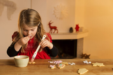 Little girl garnishing Christmas cookies with hundreds and thousands - NEKF00004