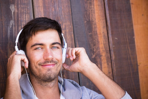 Porträt eines lächelnden jungen Mannes mit Kopfhörern - SIPF01916