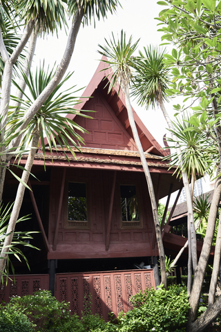 Thailand, Bangkok, rotes Haus im thailändischen Stil, umgeben von Natur, lizenzfreies Stockfoto