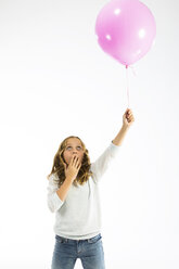 Girl playing with pink balloon, hand covering mouth - MAEF12476