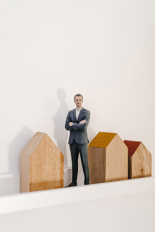 Geschäftsmann Figur stehend neben Holzhausmodellen, lizenzfreies Stockfoto