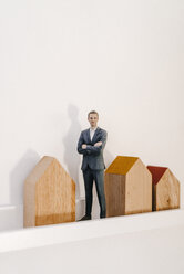 Geschäftsmann Figur stehend neben Holzhausmodellen - FLAF00001