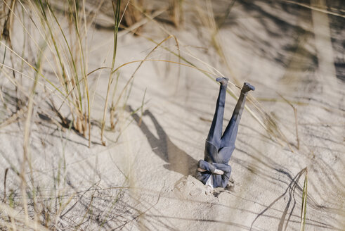 Geschäftsmannfigur, die kopfüber im Sand steckt - FLAF00002