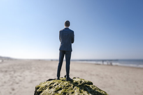 Businessman figurine standing on sand hill looking at view - FLAF00009