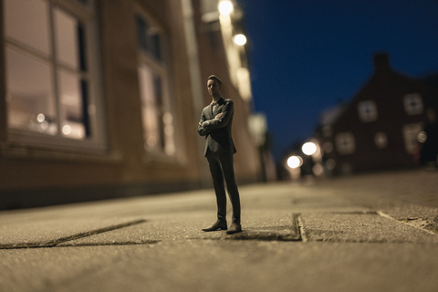 Geschäftsmann Figur in der Straße vor Häusern stehend, lizenzfreies Stockfoto