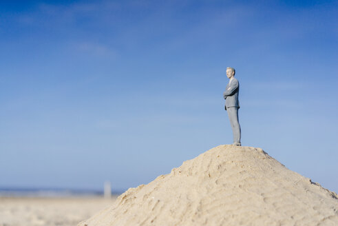 Businessman figurine standing on sand hill looking at view - FLAF00017