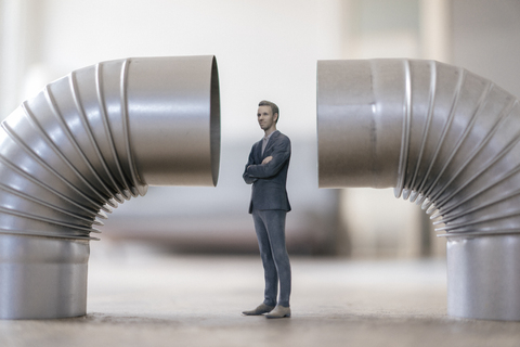 Geschäftsmannfigur zwischen zwei Ofenrohren stehend, lizenzfreies Stockfoto