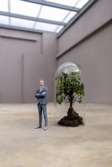 Businessman figurine standing by tree under a bell jar - FLAF00043