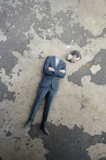 Headless businessman figurine laying on cocrete - FLAF00045