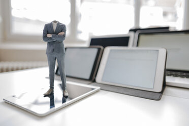 Headless businessman figurine standing on digital tablet on a desk - FLAF00047