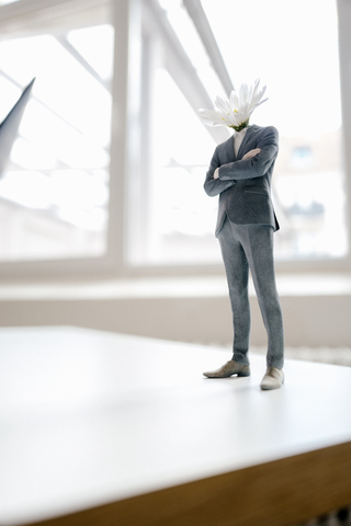 Businessman figurine with a flower head standing on desk stock photo