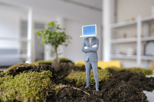 Businessman figurine with laptop head standing on green moss - FLAF00053