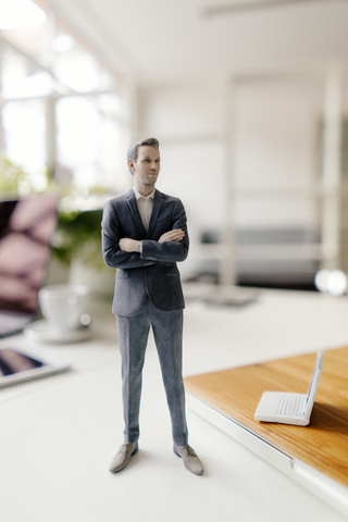 Geschäftsmann Figur stehend auf einem Schreibtisch mit mobilen Geräten, lizenzfreies Stockfoto