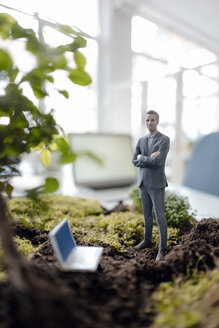 Businessman figurine with laptop standing on green moss - FLAF00064