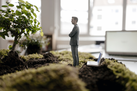 Geschäftsmann-Figur mit Laptop auf grünem Moos stehend, lizenzfreies Stockfoto