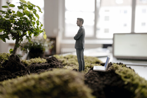 Businessman figurine with laptop standing on green moss - FLAF00065