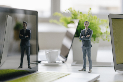 Geschäftsmann Figur stehend auf Schreibtisch mit mobilen Geräten, lizenzfreies Stockfoto