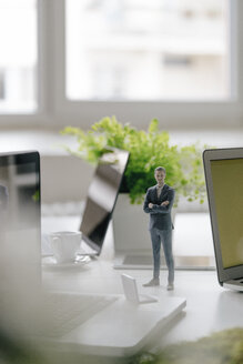 Businessman figurine standing on desk with mobile devices - FLAF00072