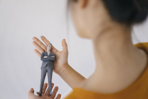 Junge Frau hält Miniaturfigur ihres Chefs - FLAF00073