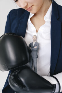 Businesswoman holding businessman figurine between boxing gloves - FLAF00074