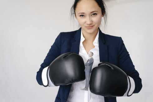 Businesswoman holding businessman figurine between boxing gloves - FLAF00075