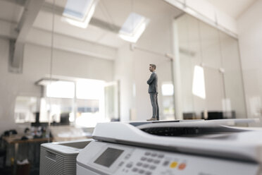 Businessman figurine standing on copy machines in modern office - FLAF00082