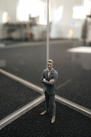 Businessman figurine standing between glass panes stock photo