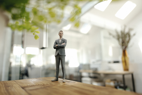 Geschäftsmann Figur stehend auf dem Schreibtisch im modernen Büro, lizenzfreies Stockfoto