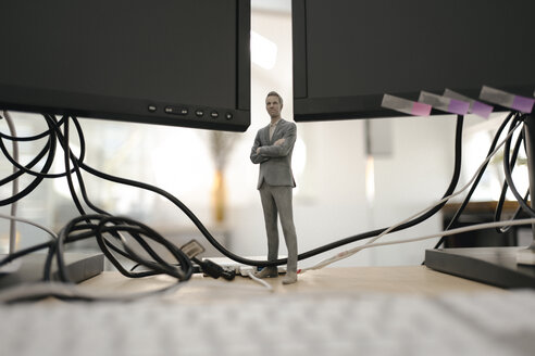 Businessman figurine standing under computer screens - FLAF00090