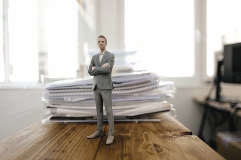 Geschäftsmann Figur stehend auf Schreibtisch mit Akten, lizenzfreies Stockfoto