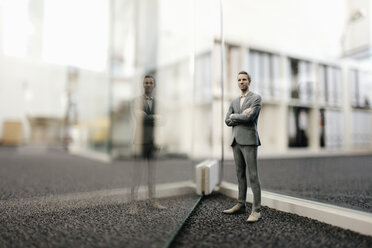 Geschäftsmann vor einer Glaswand im Büro stehend - FLAF00093