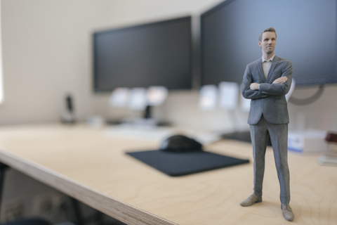 Geschäftsmann Figur stehend auf dem Schreibtisch im modernen Büro, lizenzfreies Stockfoto