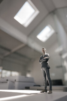 Businessman figurine standing on desk in modern office - FLAF00097