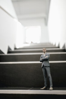 Businessman figurine standing on stairs in office - FLAF00098