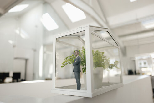 Businessman figurine standing in glasshouse with plant - FLAF00101