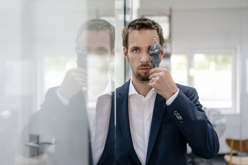 Businessman holding his 3D portrait in front of his eye - FLAF00110