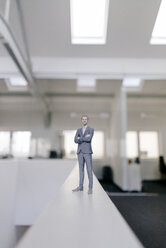 Geschäftsmann Figur stehend auf dem Schreibtisch im modernen Büro - FLAF00114