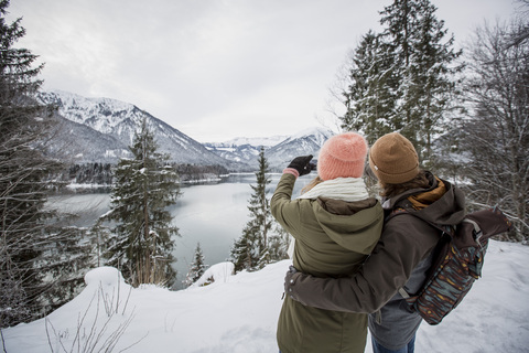 Couple taking a picture in alpine winter landscape with lake stock photo