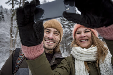 Happy couple taking a selfie in winter landscape - SUF00400