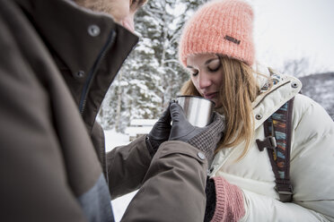 Couple sharing hot drink outdoors in winter - SUF00412