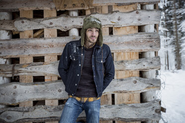 Man standing in front of wood pile outdoors in winter - SUF00423