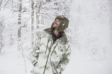 Glücklicher Mann in Tarnjacke im Winterwald - SUF00428