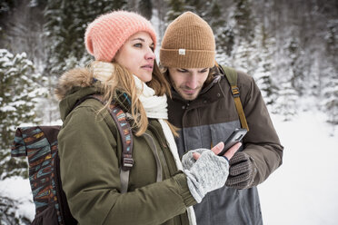 Ehepaar auf einer Reise im Winter mit Mobiltelefon - SUF00441