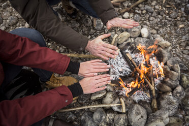 Nahaufnahme eines Paares, das sich am Lagerfeuer die Hände wärmt - SUF00452