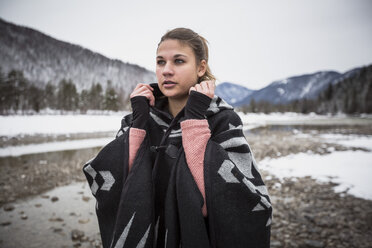 Junge Frau an einem Fluss im Winter stehend - SUF00456