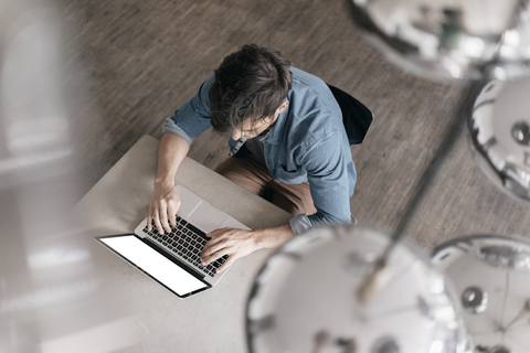 Junger Mann arbeitet am Laptop, Draufsicht, lizenzfreies Stockfoto