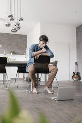 Young man using laptop in a loft - KNSF03429