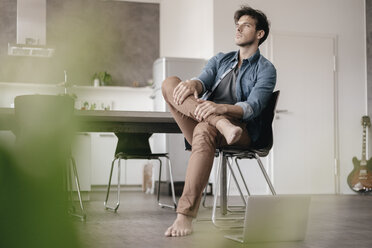 Pensive young man sitting in a loft - KNSF03440