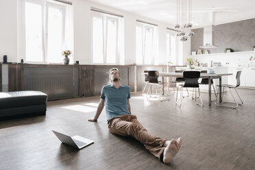 Man with eyes closed sitting on the floor in a loft relaxing - KNSF03450