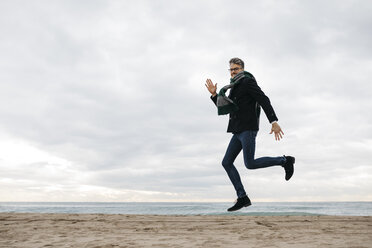 Man jumping on the beach in winter - JRFF01515